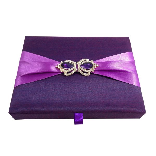 Plum color boxed wedding invitation with violet ribbon and crown brooches