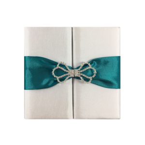 White wedding invitation with teal ribbon and rhinestone clasp