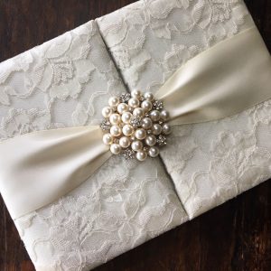 lace wedding invitations with pearl brooch and ivory lace fabric